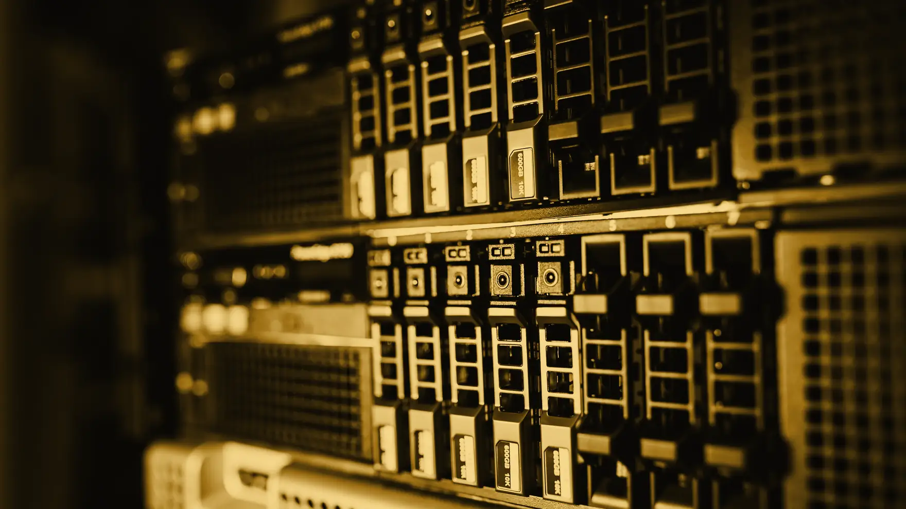 Corredor de um data center em penumbra, com fileiras de servidores iluminadas em âmbar